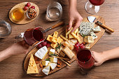 istock Women with glasses of wine and cheese plate on table, top view 1306438018