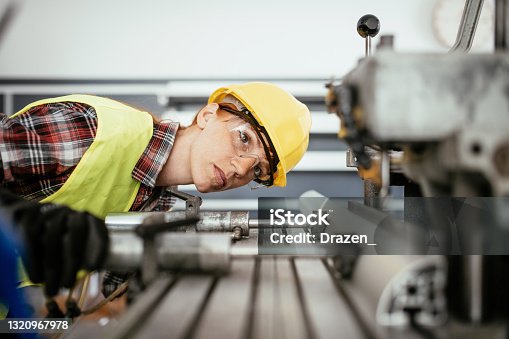 istock Women with protective equipment working on the drill in factory plant 1320967978