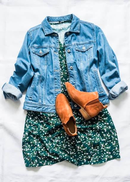 Women's clothing for spring, summer, autumn - denim jacket oversize, floral dress, suede chelsea boots on a light background, top view stock photo