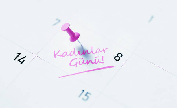 Women's Day note written in Turkish over white calendar pinned by pink push pin to remind its importance. Calendar and reminder concept. Horizontal composition with copy space. High angle view.
