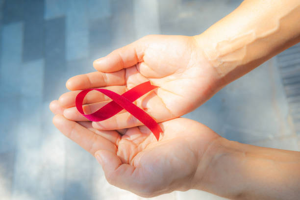 Women's hands hold the red ribbon, World AIDS Day Campaign. stock photo