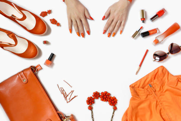 Women's hands with manicure and items of women's clothing and accessories in orange . stock photo