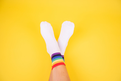 Womens legs in rainbow socks on yellow background