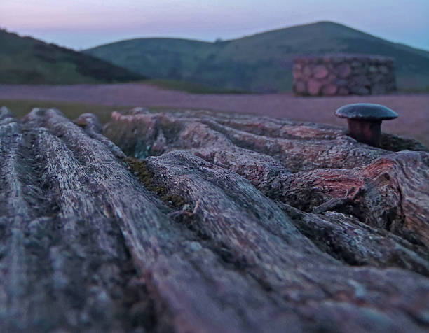 Wood And Landscape A picture of the top of a wooden bench looking at one of the Malvern Hills, with a rivet showing during sunset. normalisaverage stock pictures, royalty-free photos & images