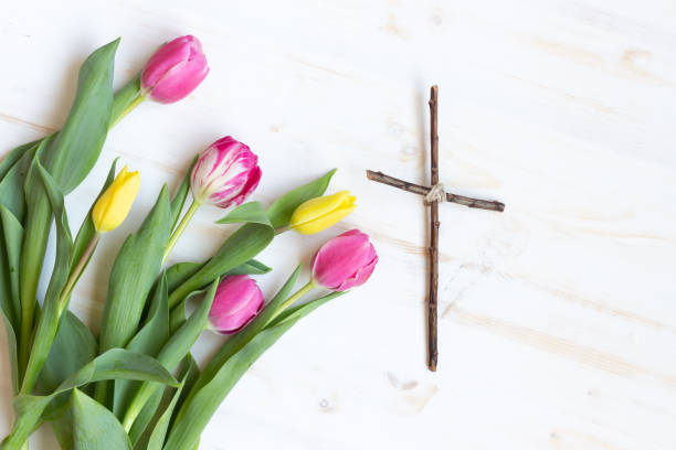 Wood cross and tulips laying on white wood  easter sunday stock pictures, royalty-free photos & images