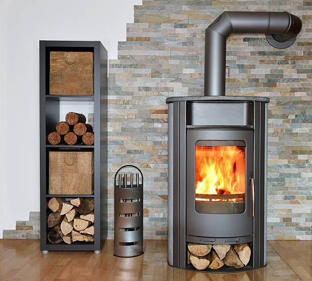 wood fired stove while burning wood fired stove with fire-wood, fire-irons, and briquettes from bark chimney stock pictures, royalty-free photos & images