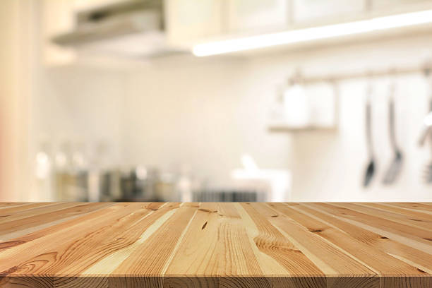 wood table top (kitchen island) on blur kitchen interior background - kookeiland stockfoto's en -beelden