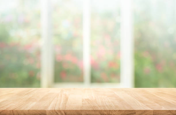 Wood table top on blur of window with garden flower stock photo