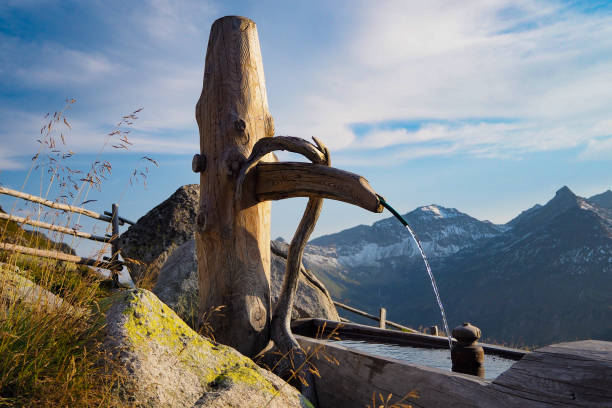 wooden alpine water fountain with Hohe Tauern mountain range in the back, Austria wooden alpine water fountain with Hohe Tauern mountain range in the back, Austria osttirol stock pictures, royalty-free photos & images