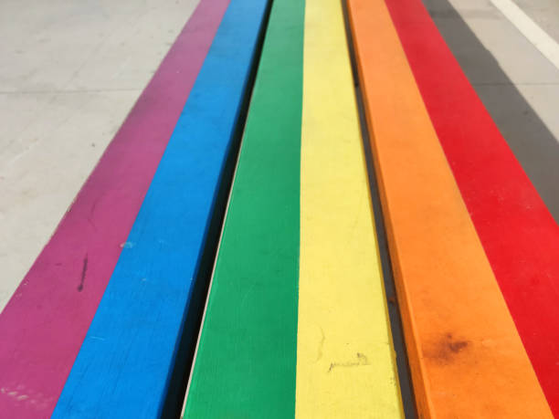 해변에서 무지개 색으로 그려진 나무 벤치 - progress pride flag 뉴스 사진 이미지