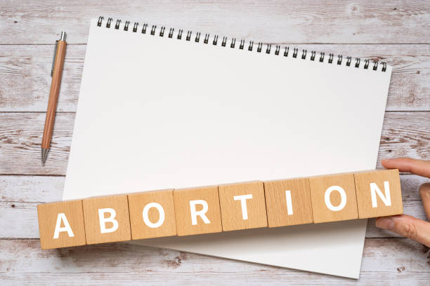 bloques de madera con texto conceptual "aborto", un bolígrafo y un cuaderno. - abortion clinic fotografías e imágenes de stock