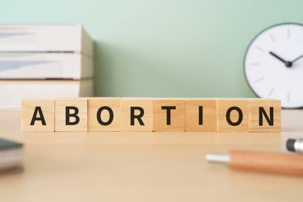 bloques de madera con texto de concepto "aborto", bolígrafos, cuadernos y libros. - abortion clinic fotografías e imágenes de stock