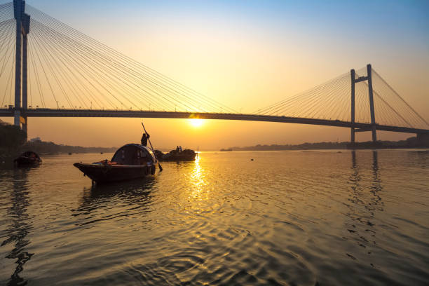 Wooden boats near the Vidyasagar Setu (bridge) on river Hooghly at sunset. Vidyasagar Setu also known as the Second Hooghly bridge is the longest cable stayed bridge in India. Photograph taken from Princep Ghat on the banks of river Hooghly. kolkata stock pictures, royalty-free photos & images