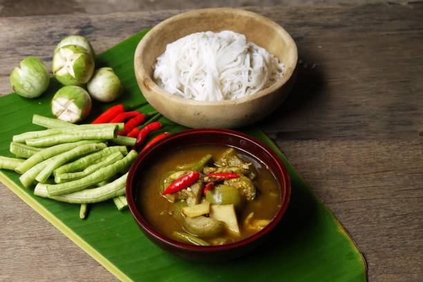 Wooden bowl of Fish organs sour soup  and Rice Noodles on banana leaf  with vegetables  in the kitchen prepare for serving ,Thai local food image for background , selective stock photo