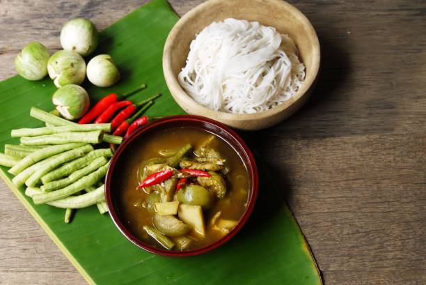 Wooden bowl of Fish organs sour soup  and Rice Noodles on banana leaf  with vegetables  in the kitchen prepare for serving ,Thai local food image for background , selective stock photo