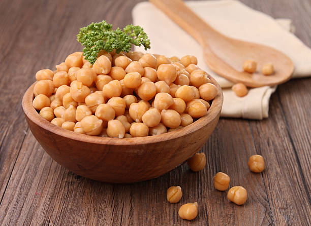 Wooden bowl overflowing with chickpeas topped with parsley stock photo