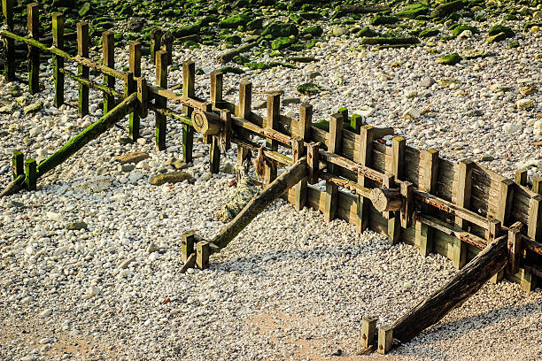 Wooden Breakwater Groynes at pebble beach stock photo