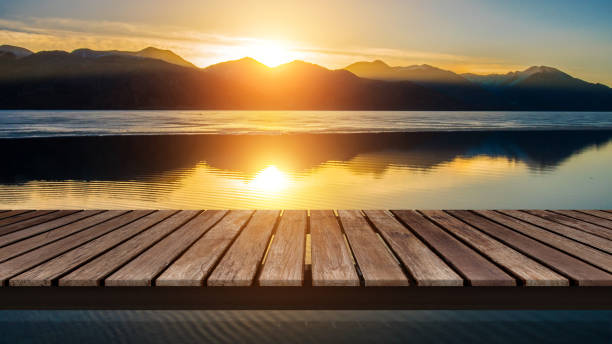 Photo of Wooden bridge on the lake with a reflection of sunset on the snow mountain