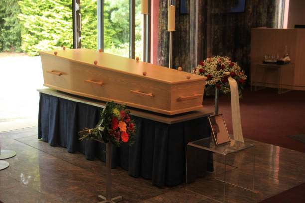 Wooden casket with funeral flowers Plain light wooden coffin in a crematorium cremation stock pictures, royalty-free photos & images