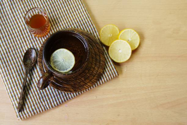 Wooden  cup  of herbal  tea  on wooden table  with lemon and honey , selective focus. stock photo