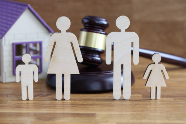 Wooden figurines of parents and children stand on table near toy house and judges hammer stock photo