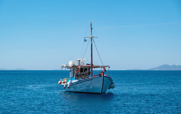 Wooden fishing boat moored in Aegean sea, blue sky background. Koufonisi Greek island, Cyclades. stock photo