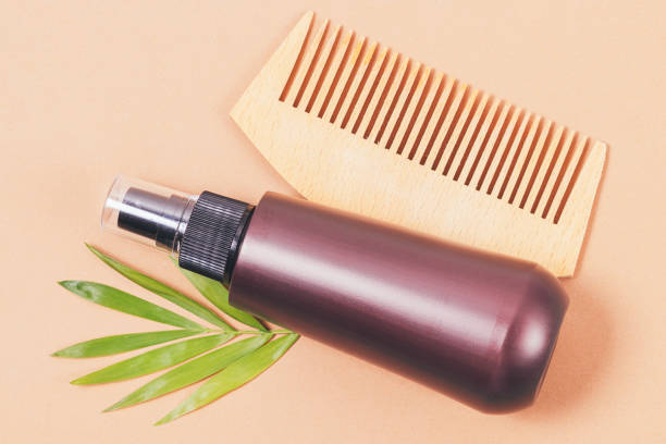 Wooden hair comb and natural cosmetic spray with green leaf stock photo