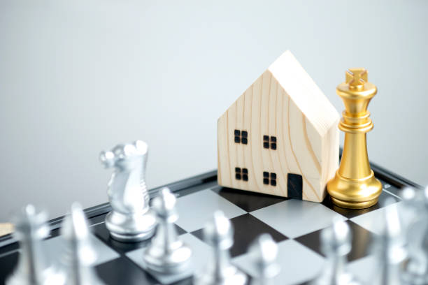 Wooden house model with a gold king chess on a chessboard stock photo
