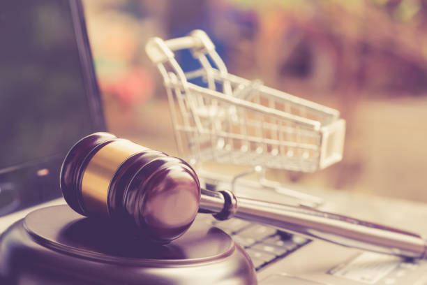wooden judge gavel and shopping cart on a laptop - consumismo imagens e fotografias de stock