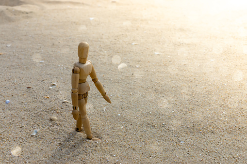 wooden models feel lonely on the beach with sunlight and space for text.