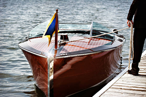 Wooden Motor Boat A docked wooden motor boat.  A man stands on the dock holding the mooring line. moored stock pictures, royalty-free photos & images