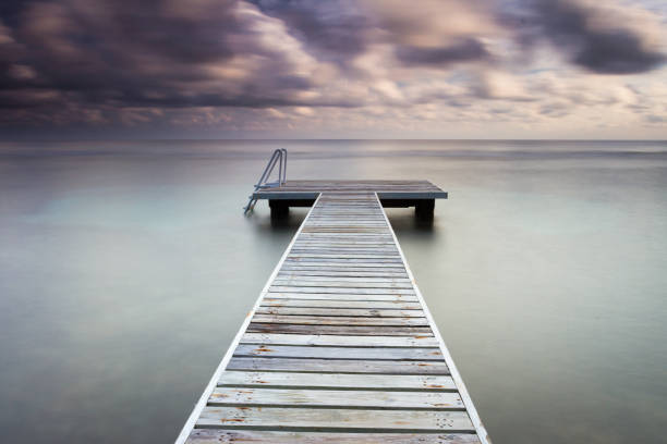 wooden pier at sunrise taken with a long exposure stock photo