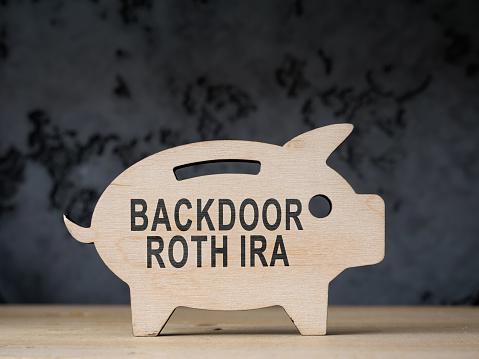 A Wooden piggy bank with words backdoor Roth IRA.