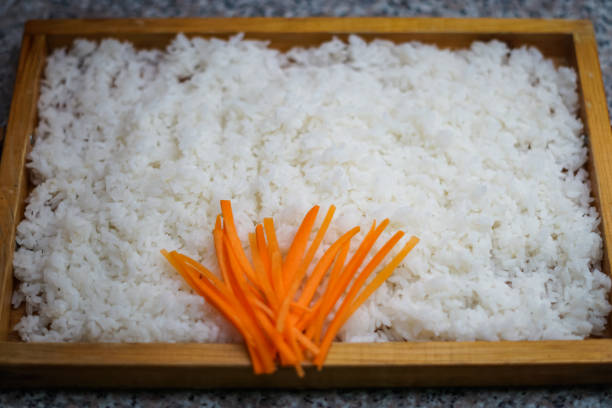 A wooden plate of rice with some carrots stock photo