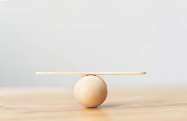 木製のシーソースケールは、木製のテーブル上の木製の球体に空のバランス - バランス ストックフォトと画像