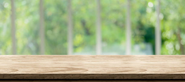 wooden table background with blur window see through garden at home.Mockup banner space for product display for advetising at online media stock photo