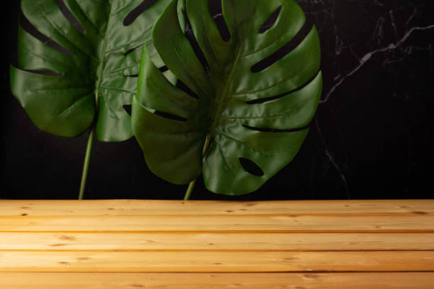 wooden table, Monstera leaves and dark rugged background. stock photo