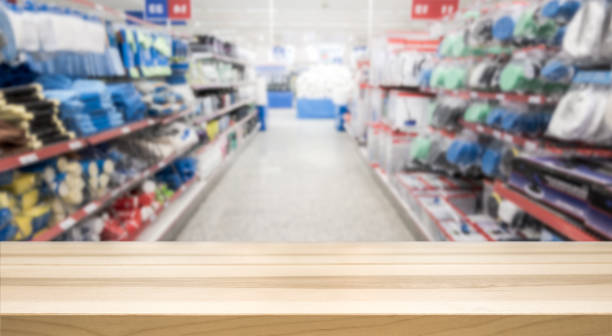 Wooden table top in front of blurred hardware and grocery store. Wooden table top in front of blurred hardware and grocery store. Background for product display montage. Copy space design. construction material stock pictures, royalty-free photos & images