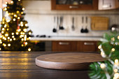 istock Wooden tabletop with cutting board and blurred modern kitchen with Christmas tree. 1284888548