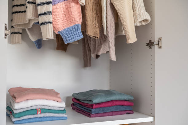 Woolen knit sweaters stacked and hanged in wardrobe stock photo