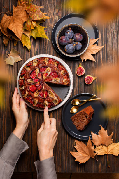 Wooman hands cutting a homemade sweet baked pie with figs and bananas. Autumn background. Flat lay, top view. stock photo