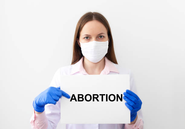 abortion wort auf weißem papier von einem arzt auf weißem hintergrund gehalten - my body my choice abortion stock-fotos und bilder