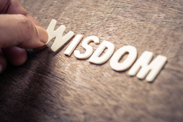 WISDOM word Closeup hand place the wood letters as WISDOM word on wood background wisdom stock pictures, royalty-free photos & images