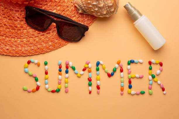 Word summer written with colorful candies on orange background with sunglasses and summer hat for the seaside stock photo