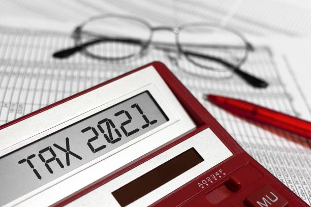계산기에 단어 세금 2021. 문서에 안경, 펜 및 계산기. 금융안정의 개념,소득명세서 - taxes 뉴스 사진 이미지