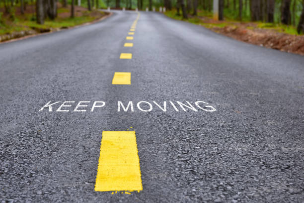 Words of keep moving with yellow line marking on road surface stock photo