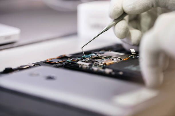 Work with a microscope. Microelectronics device. Close-up hands of a service worker repairing modern smartphone. Repair and service concept. stock photo