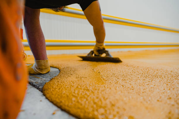 Worker applying epoxy and polyurethane flooring system.These easy-to-clean products also have non-slip features.  floor epoxing stock pictures, royalty-free photos & images