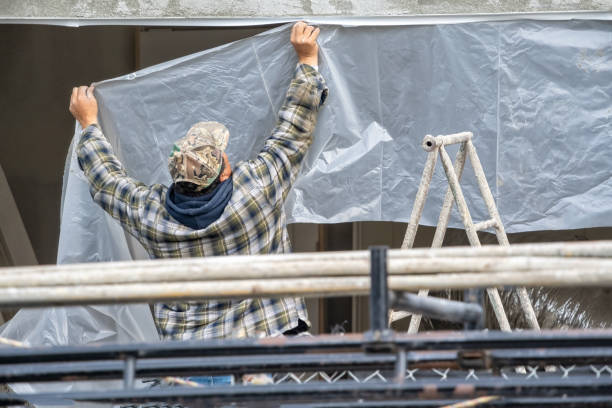 Worker covering a wall with masking tape and plastic sheeting for protection during a home construction. and remodeling. stock photo