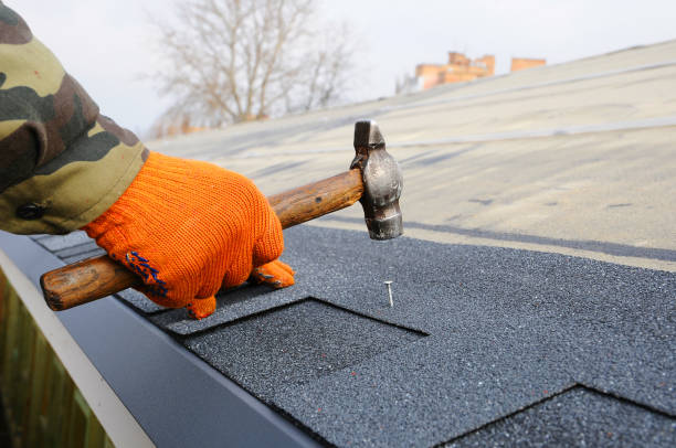 Worker hands installing bitumen roof shingles using hammer in nails. stock photo